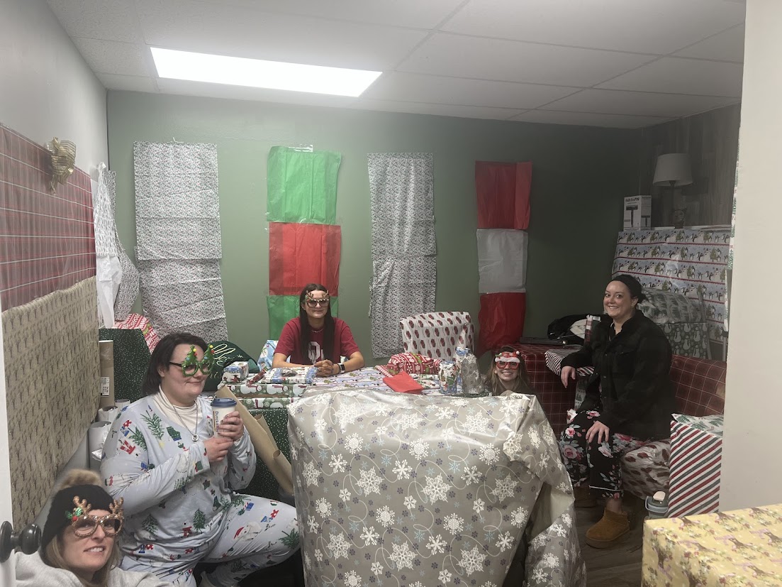 Solari Professionals setting in the office with Christmas shaped glasses on. Everything in the office is wrapped in paper.