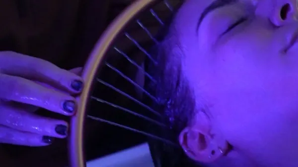 Head spa stylist using the "halo" to guide the stream of water over the scalp of a relaxed client.